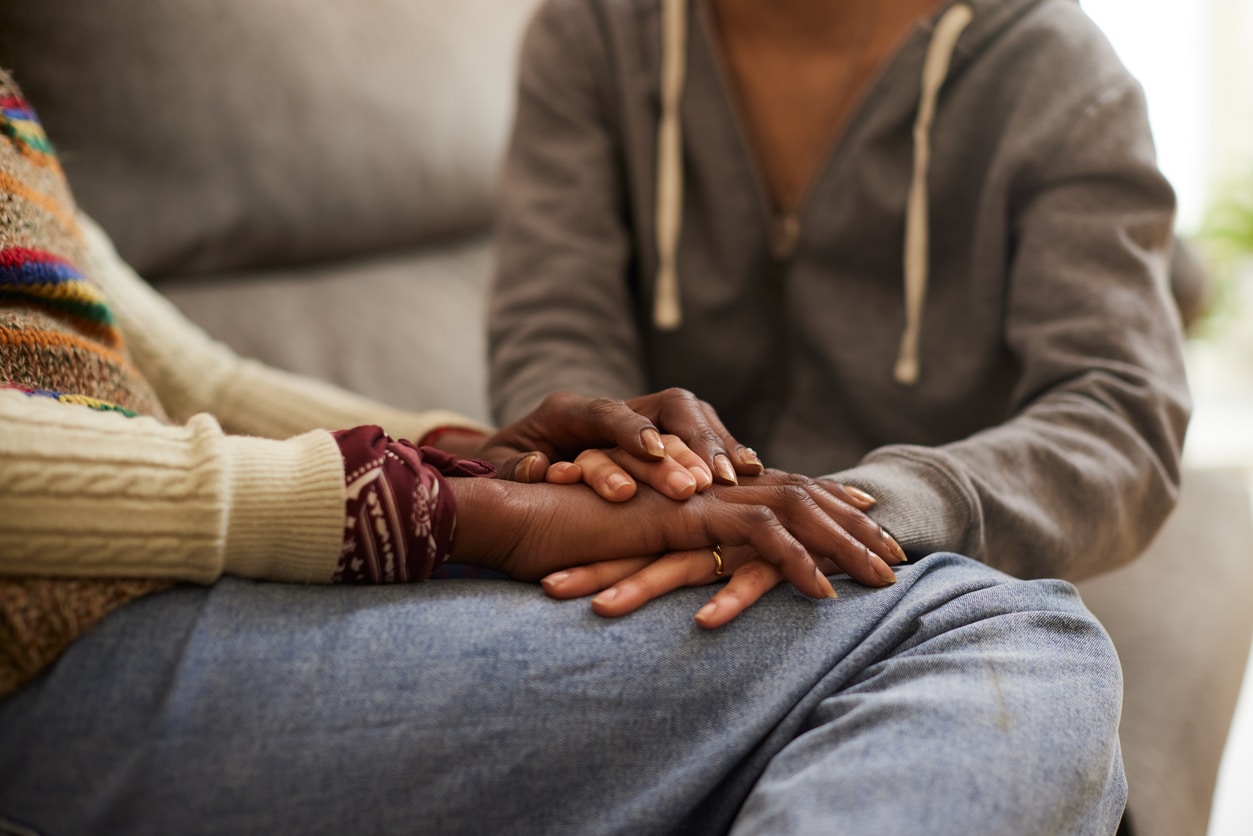 Daughter holding mother hands and comforting her