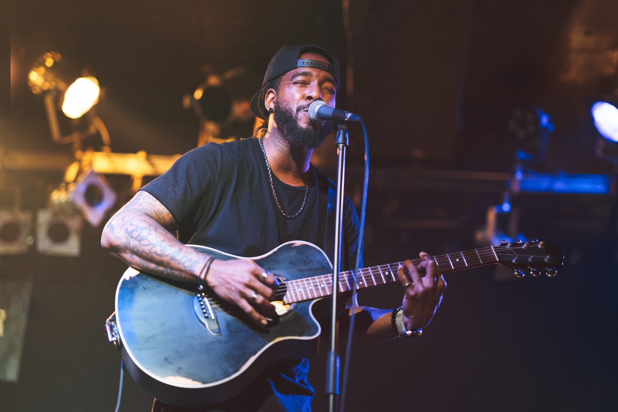 Man playing acoustic guitar and singing on stage.