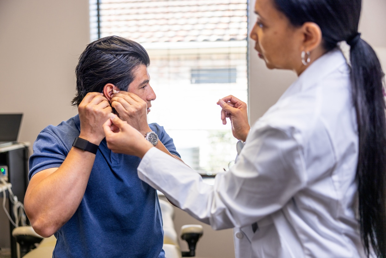 Man removing his hearing aid at the audiologist.