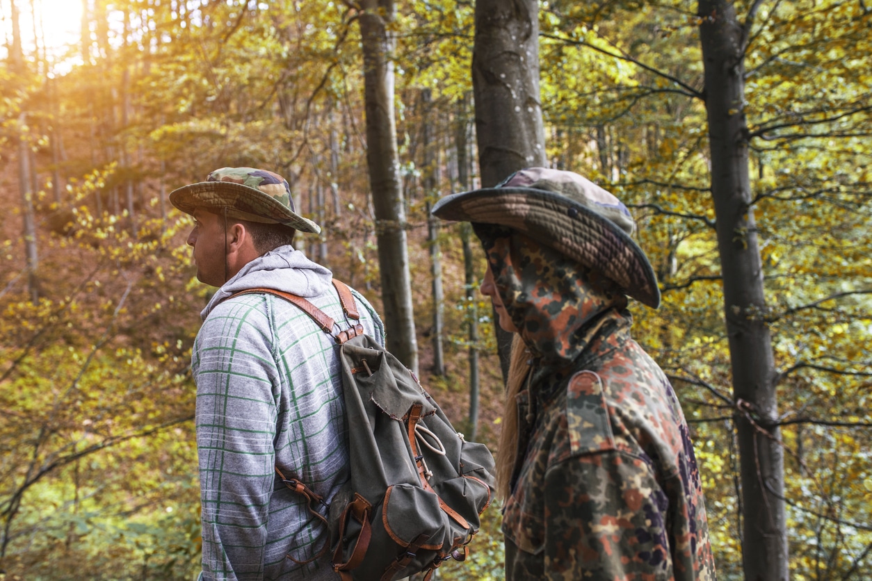 Two people in the woods, one in camo
