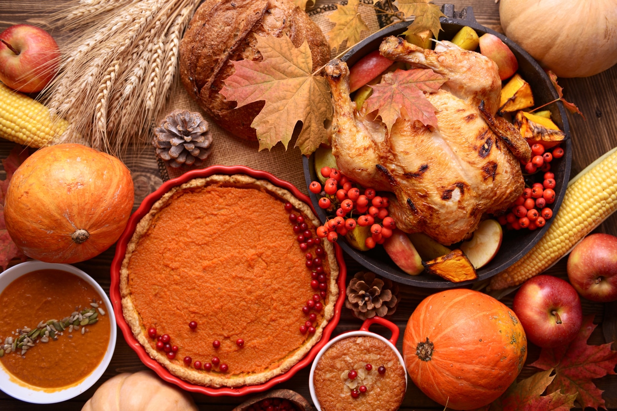 Traditional Thanksgiving still life. Roasted turkey, pumpkin pie, cranberries, autumn pumpkins and nuts on a dark wooden table. Top view.